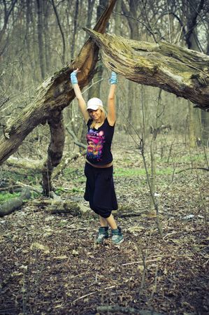 beautiful young girl standing under a fallen tree in the forestの写真素材