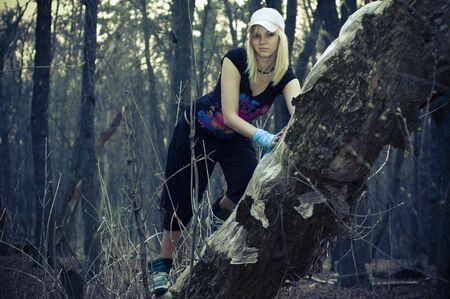 beautiful young girl leaned on a tree trunk in the forestの写真素材
