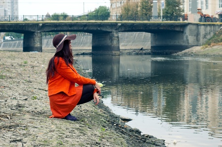 girl in a hat sits on the banks of the river の写真素材