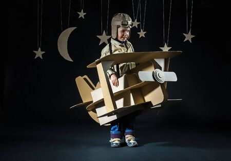 Boy is playing with handmade toy plane. Background â decorations of night skyの写真素材