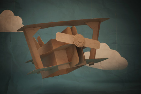 Hand made airplane made of cardboard on blue sky with paper clouds.の写真素材