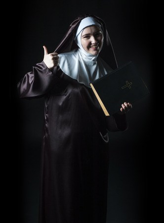 Young nun advertises bible and shows thumbsの写真素材