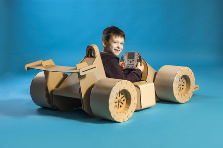 photo of  young racer on a cardboar racing car on blue backgroundの写真素材
