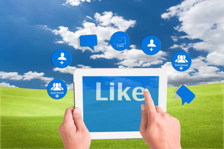 hand holding a touchpad pc and press like button with mail , add friend and comment icons