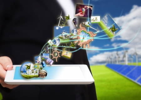 saving energy stream images from tablet pc on the field with solar cell and wind turbine の写真素材