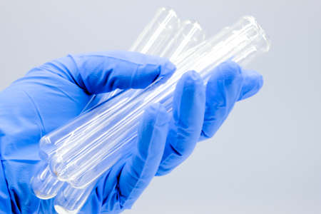 Laboratory test tubes in hand in blue gloves on a white background