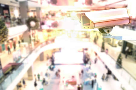 CCTV security camera or surveillance system in shopping mall, blurred background