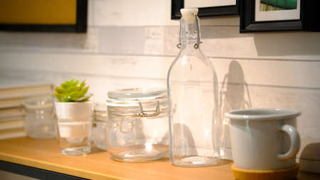 Glass of water with a bottle on table. Clear glass bottles and containers of various sizes and shapes.の写真素材