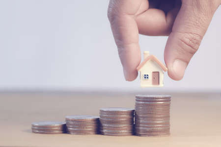 Money coins saving for concept investment mortgage fund finance and home loan refinance, savings plans for housing, house mortgage financial concept, Money coin stack with house.の写真素材