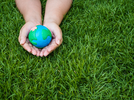 earth day. earth in hands and green grass field background. environment save earth concept.の写真素材