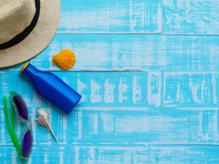 Beach accessories including sunglasses, sunscreen, hat beach, shell on bright blue wooden background for summer holiday and vacation concept.の写真素材