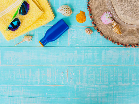 Beach accessories including sunscreen, hat beach, shell, yellow towel and retro camera on bright...