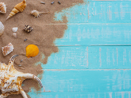 Beach accessories including hat beach, shell, sand on bright blue pastel wooden background for summer holiday and vacation concept.の写真素材