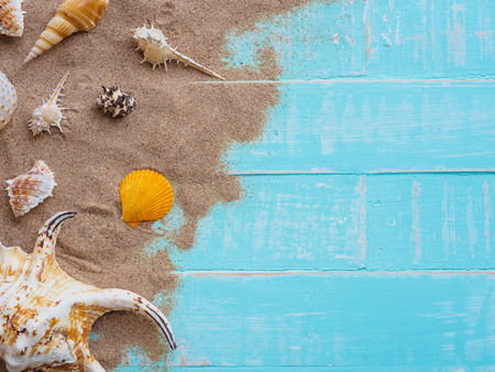 Beach accessories including hat beach, shell, sand on bright blue pastel wooden background for summer holiday and vacation concept.の写真素材