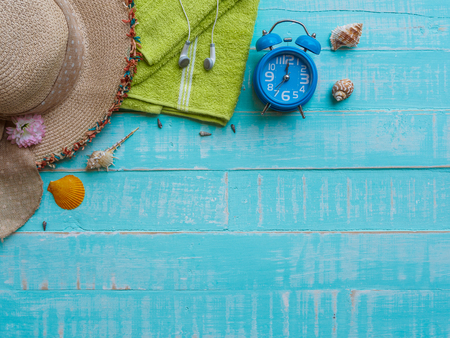 Beach accessories including sunscreen, hat beach, shell and retro camera on bright blue pastel wooden background for summer holiday and vacation concept.の写真素材