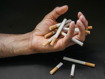 Man hand holding and destroy cigarettes on black background. Quitting smoking concept. world no tobacco dayの写真素材
