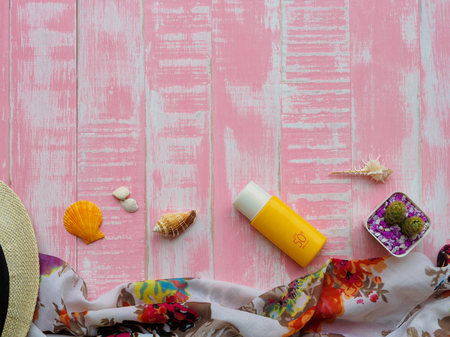 Beach accessories including sunscreen, hat beach, shell and retro camera on bright pink pastel...