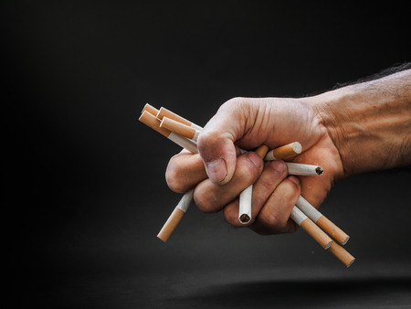 Man hand holding and destroy cigarettes on black background. Quitting smoking concept. world no tobacco dayの写真素材