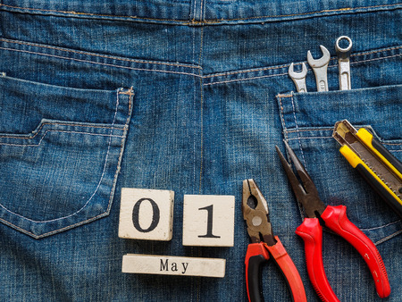 wooden block calendar 1 May and Joinery tools on a jean texture background. Labor day concept.