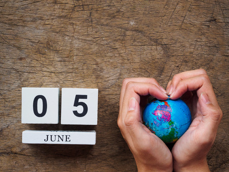 05 JUNE wooden calendar block, globe and hand on wooden texture background top view. World Environment day concept.の写真素材