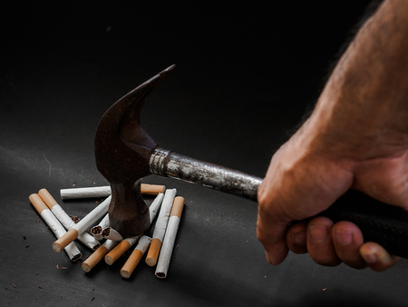 Hammer hitting and destroy cigarettes on black background. Quitting smoking concept. world no tobacco dayの写真素材