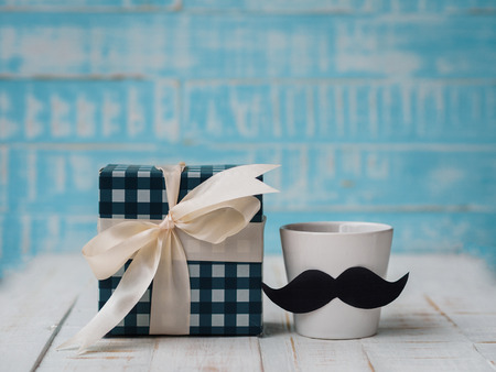 Happy father's day concept. gift box, a cup of coffee with mustache on white and blue background.の写真素材
