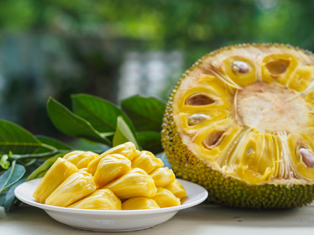 Fresh Jackfruit in white dish, half of jack fruit and jackfruit leaf on wooden table.の写真素材
