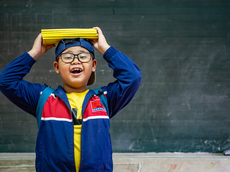 Happy Boy wear glasses smiling and stand in front of the blackboard. Back to School, Education Concept.の写真素材