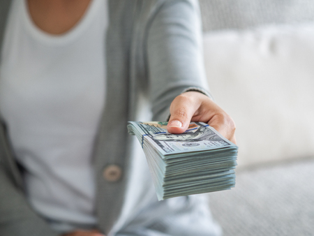 Soft focus on woman hands proposing money us dollar bills to you.の写真素材