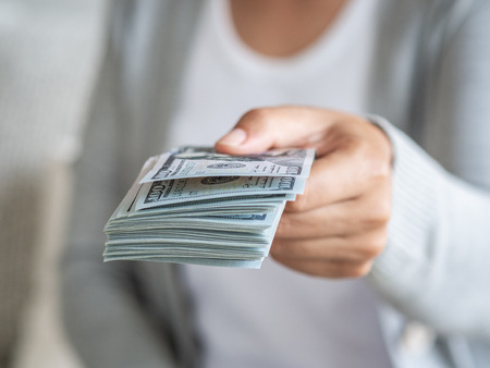 Soft focus on woman hands proposing money us dollar bills to you.