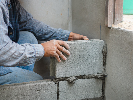 professional construction worker laying bricks with cement.の写真素材