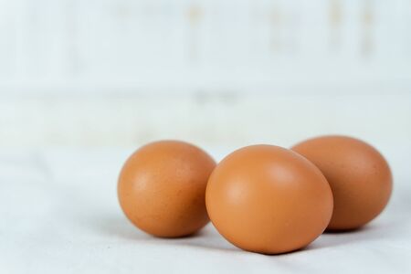 Close-up of raw chicken eggs on white wooden background.