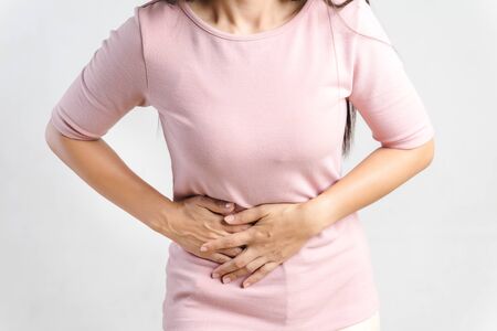 Young beautiful woman having painful stomachache on white background.Chronic gastritis. Abdomen bloating concept.の写真素材