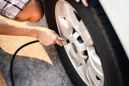 Close up of asian man inflating tire in the gas station.