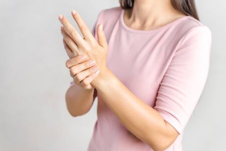 Closeup young woman holds her wrist on white background. hand injury, feeling pain. Health care and medical concept.の写真素材