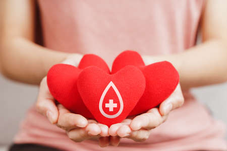 Woman hands holding red heart with blood donor sign. healthcare, medicine and blood donation conceptの写真素材