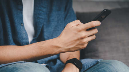 Young Asian man using smartphone typing, chatting conversation. Social Network, technology concept.の写真素材