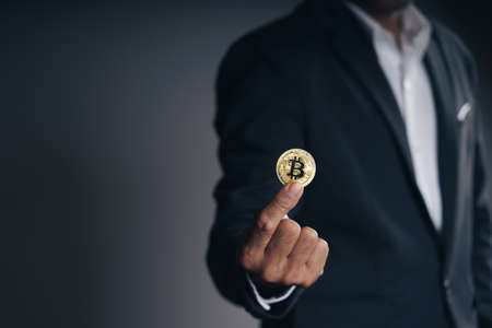 Handsome Investor Businessman in black suit holding a golden bitcoin on dark background, trading, Cryptocurrency, Digital virtual currency, alternative finance and investment Concept.の写真素材