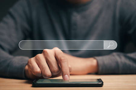 Man using a smartphone to Searching for information with the Search bar, Web browser, Data Search, Search Engine, Technology Conceptの写真素材