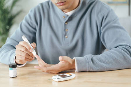 Man using lancet on finger for checking blood sugar level by Glucose meter, Healthcare and Medical, diabetes, glycemia conceptの写真素材