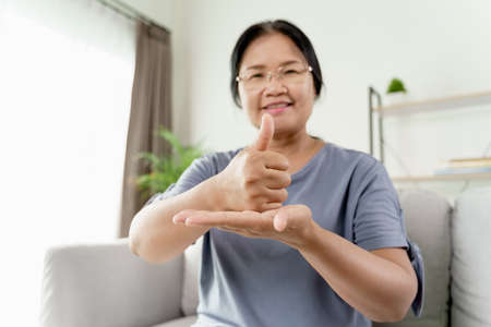Mature Asian deaf disabled woman using Sign Language to communicate with other people.の写真素材