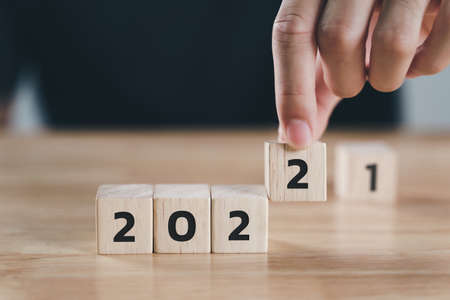 Man hand putting  wooden cube block to change 2021 year to 2022 year on wood table with copy space. start to year 2022. happy new years concept.の写真素材