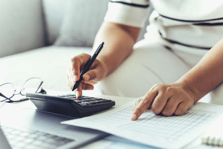 Woman is calculating annual tax with calculator and filling form of Individual Income Tax Return....