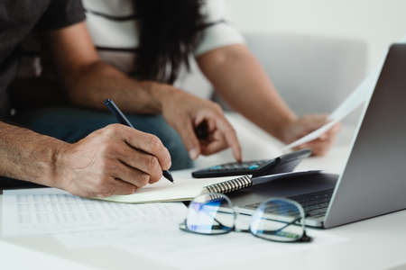Man and woman are calculating annual tax with calculator and filling form of Individual Income Tax...