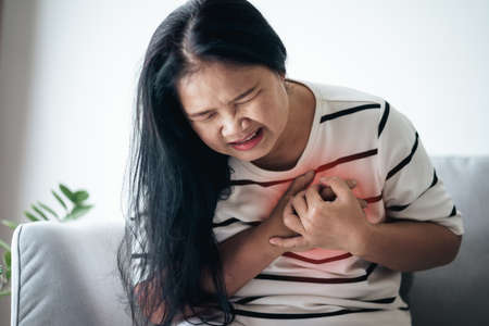 Closeup of Asian woman having heart attack. Woman touching breast and having chest pain. Healthcare And Medical concept.の写真素材