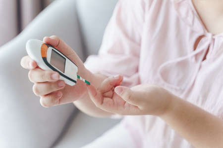 Asian woman checking blood sugar level by Digital Glucose meter, Healthcare and Medical, diabetes, glycemia conceptの写真素材