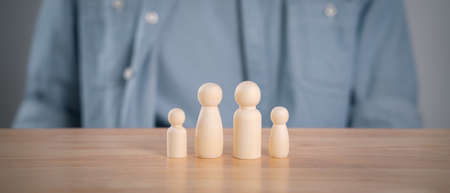 The man and wooden peg dolls on the table. planning, saving family,  health care and insurance, family mental health, international day of familiesの写真素材