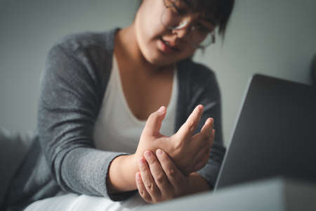 woman holding her hand pain from using computer long time. Office syndrome concept.の写真素材