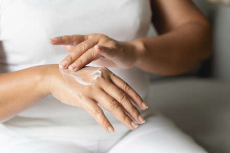 Woman applying body lotion moisturizer on her hands.の写真素材