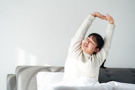 Happy Woman stretching her arms on the bed in the morning.の写真素材